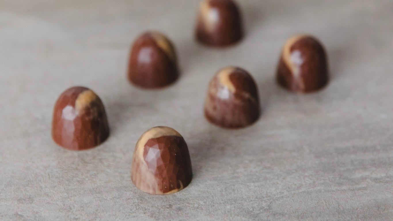 Chocolate caramel pralines on a light wooden surface