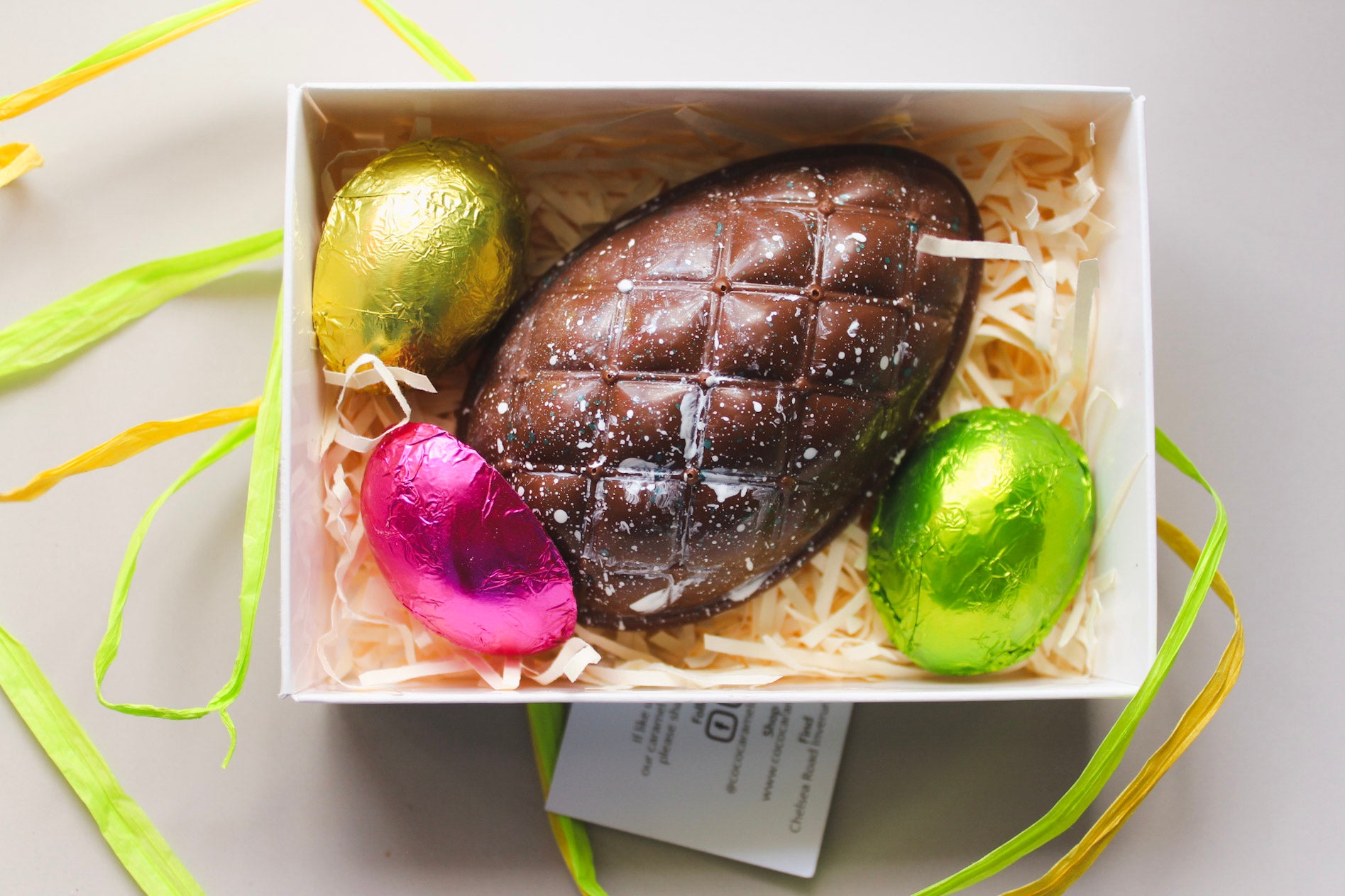Box of chocolate Easter eggs with colorful foil-wrapped eggs on a light background