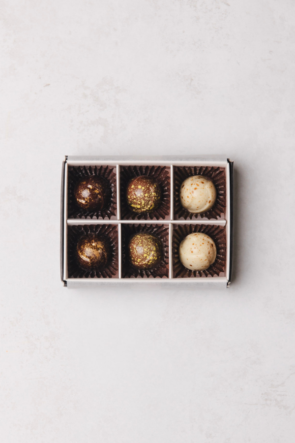 Box of chocolates with six individually wrapped pieces on a light gray background